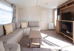 A living room with a sofa, a coffee table, a television, and a radiator.