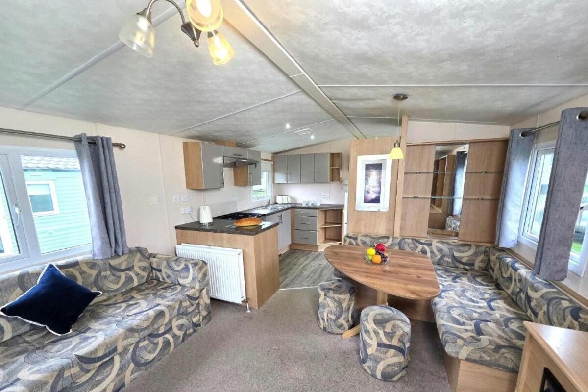 A compact RV interior with a kitchenette, a dining area, and seating arrangements.