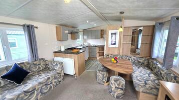 A compact RV interior with a kitchenette, seating area, and a dining table.