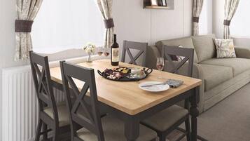 Uma sala de jantar com mesa de madeira, cadeiras, uma garrafa de vinho e um prato com comida.