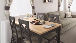 A dining area with a wooden table, chairs, a bottle of wine, and a plate with food.