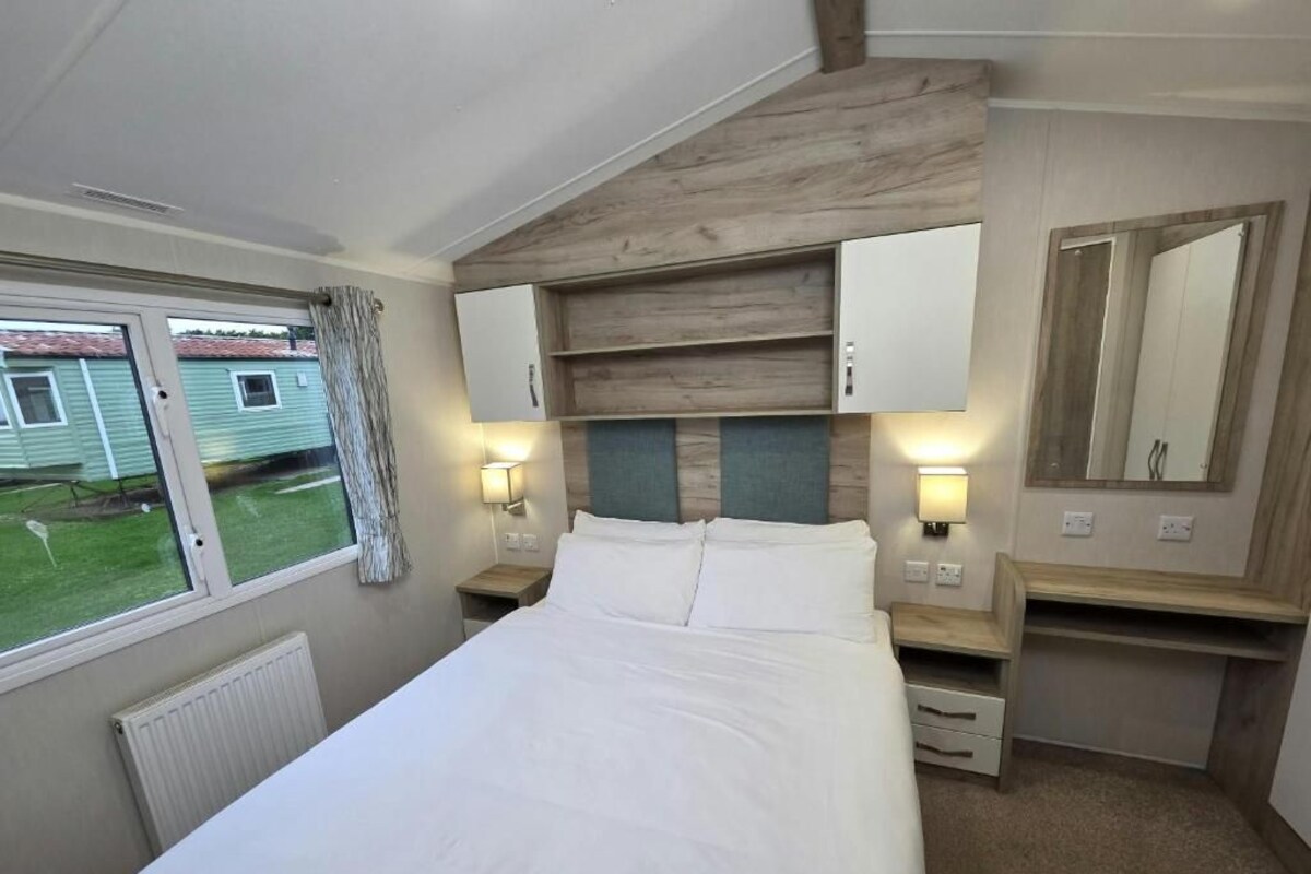 A bedroom with a bed, bedside tables, a mirror, and a window with curtains.