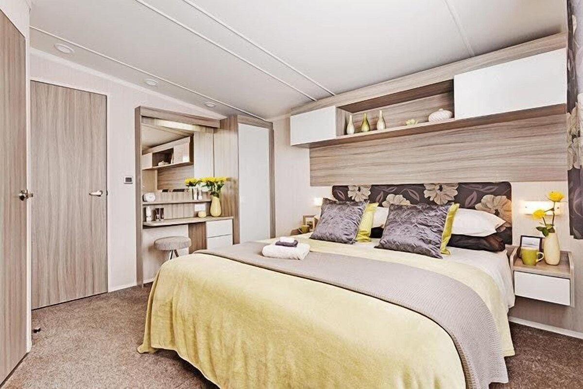 A modern bedroom with a bed, bedside tables, a vanity, and a wardrobe.