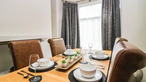 A dining area with a wooden table set for four, including plates, glasses, cutlery, and small potted plants. - Cumbria Townhouse (Workington)