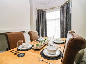 A dining area with a wooden table set for four, including plates, glasses, cutlery, and small potted plants. - Cumbria Townhouse (Workington)
