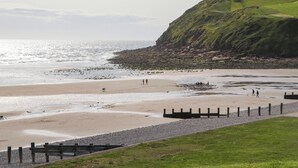 A coastal beach with a grassy area and a rocky cliff. - Cumbria Townhouse (Workington)