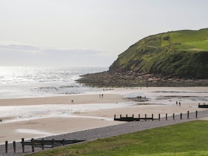 A coastal beach with a grassy area and a rocky cliff. - Cumbria Townhouse (Workington)