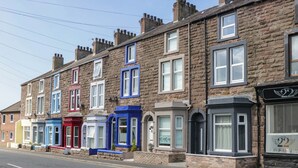 A row of terraced houses with distinct architectural styles and varying window designs. - Cumbria Townhouse (Workington)