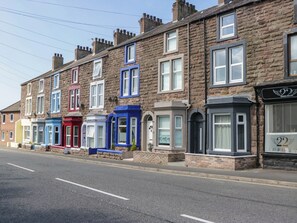 A row of terraced houses with distinct architectural styles and varying window designs. - Cumbria Townhouse (Workington)