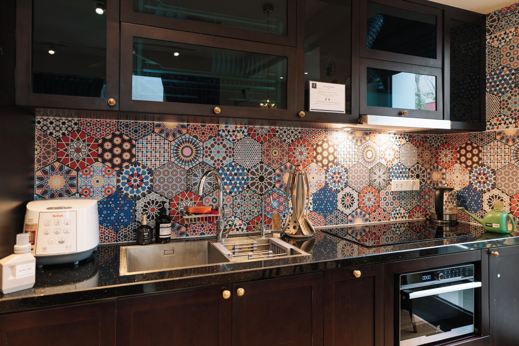 Una cocina con salpicadero decorativo, electrodomésticos de acero inoxidable y armarios de madera.