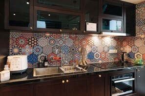 Una cocina con salpicadero decorativo, electrodomésticos de acero inoxidable y armarios de madera.