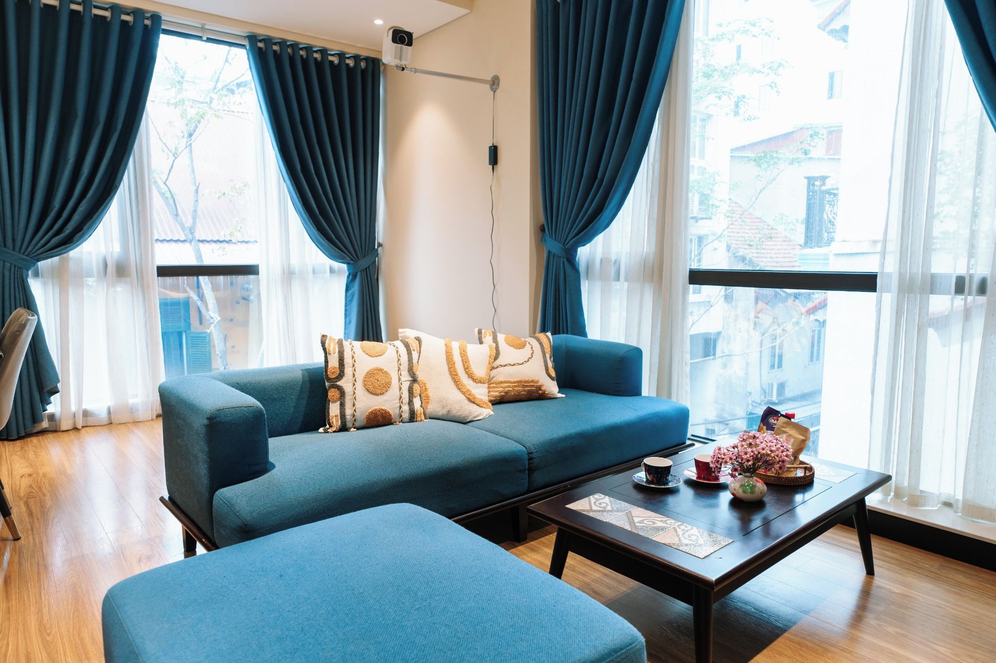 Een moderne woonkamer met een blauwe bank, een bijpassend voetenbankje en een salontafel.