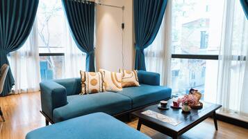 Een moderne woonkamer met een blauwe bank, een bijpassend voetenbankje en een salontafel.