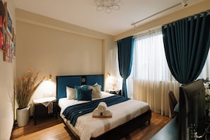 Ett hotellrum med en säng, sängbord, ett skrivbord och gardiner.