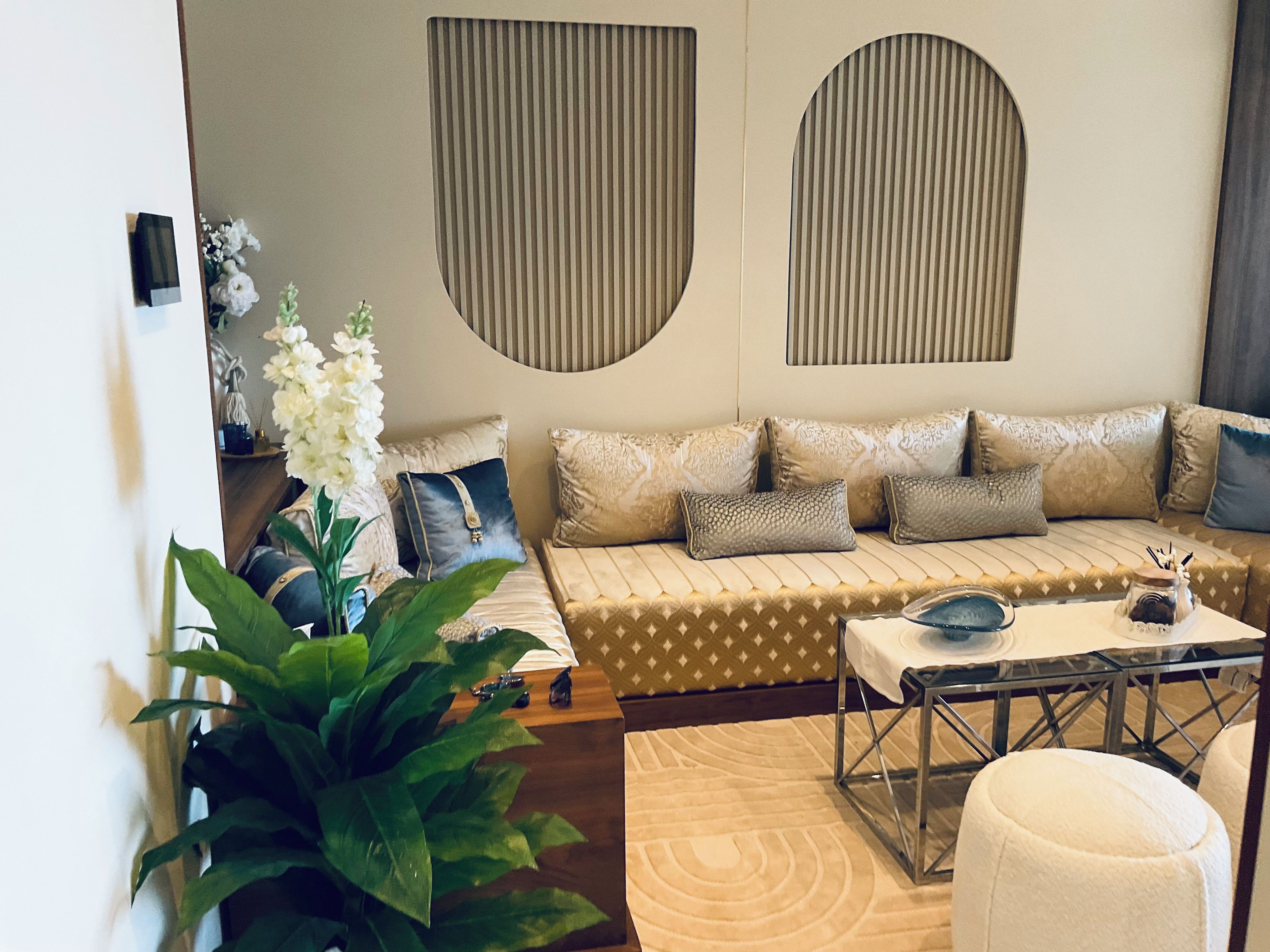 A modern living room with a sofa, decorative pillows, a coffee table, and a large plant.