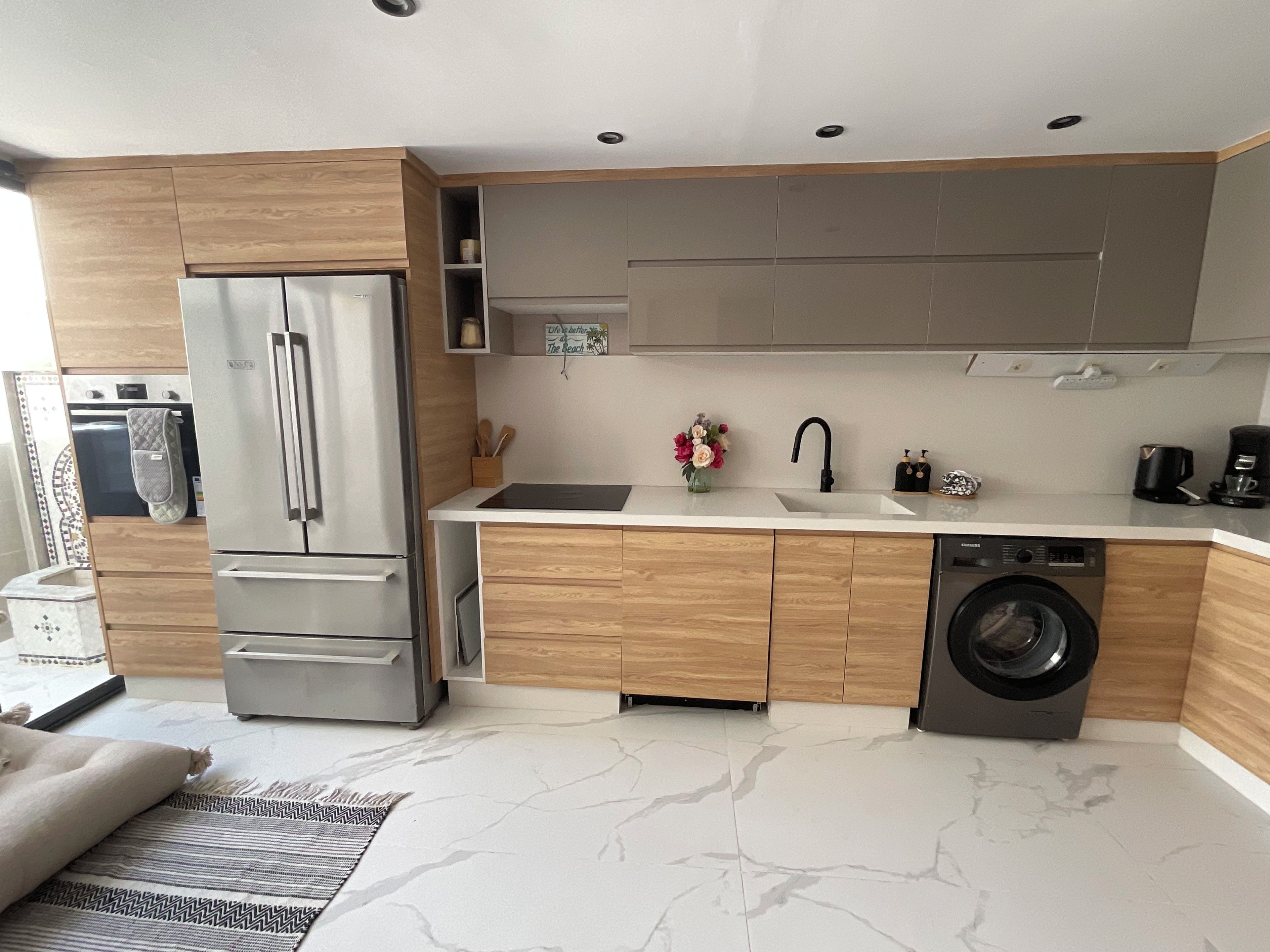 A modern kitchen with a built-in oven, refrigerator, sink, and washing machine.
