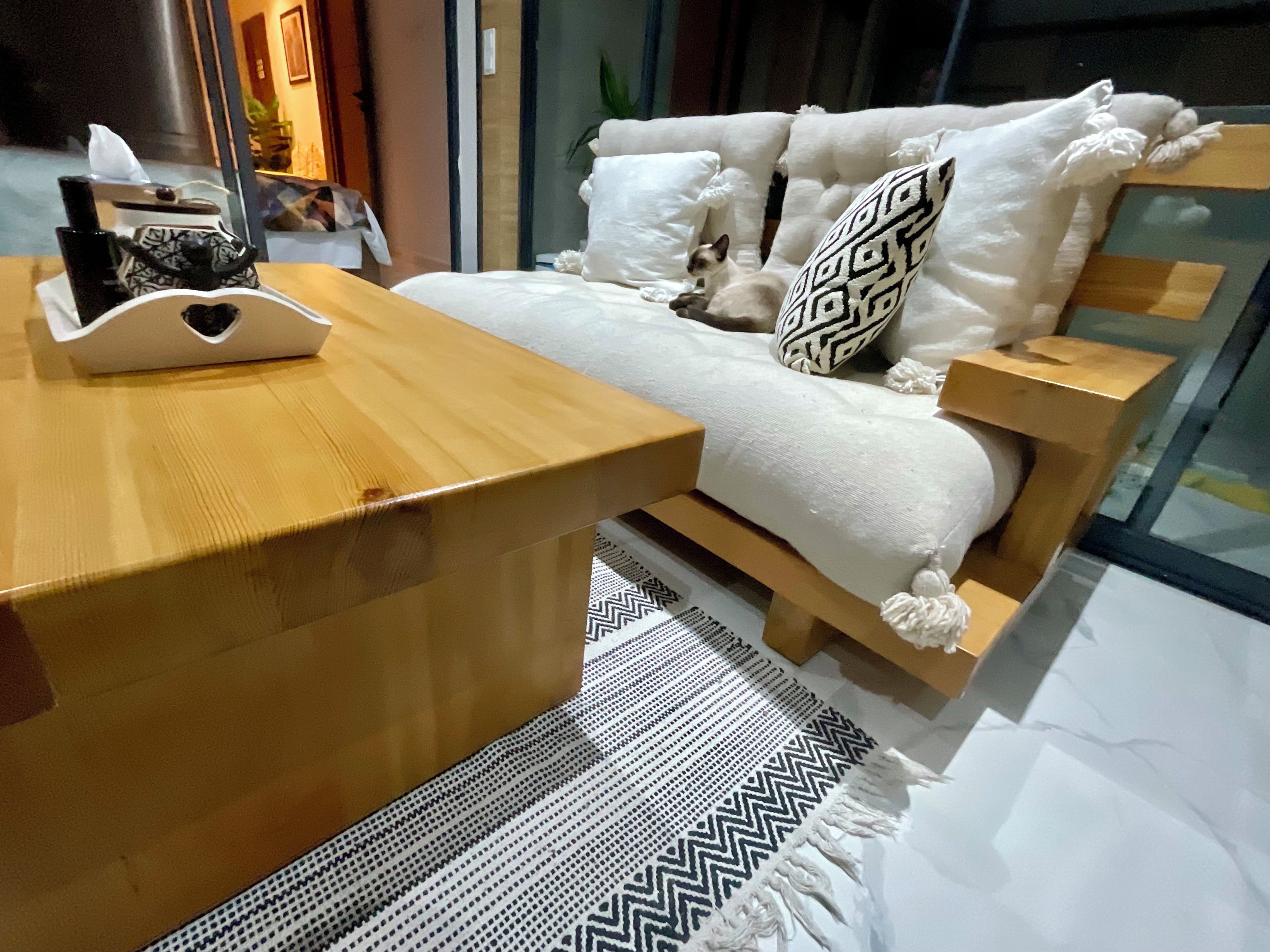 A modern bedroom with a wooden bed, white bedding, a patterned throw, and a wooden nightstand.