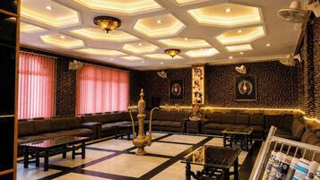A lounge area with a patterned ceiling, sofas, tables, and a magazine rack.