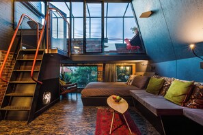 A loft-style bedroom with a large bed, a red sofa, and a small table. - The Loft - A Design Stay in Battery Point (Battery Point)