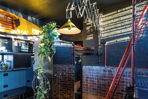 A kitchen with brick walls, a hanging plant, and a red ladder. - The Loft - A Design Stay in Battery Point (Battery Point)