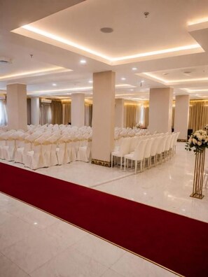 A spacious hall with rows of white chairs, a red carpet, and a decorative floral arrangement. - Elaf Al Sharqyah Al Aziziah Hotel  (Al Khobar)
