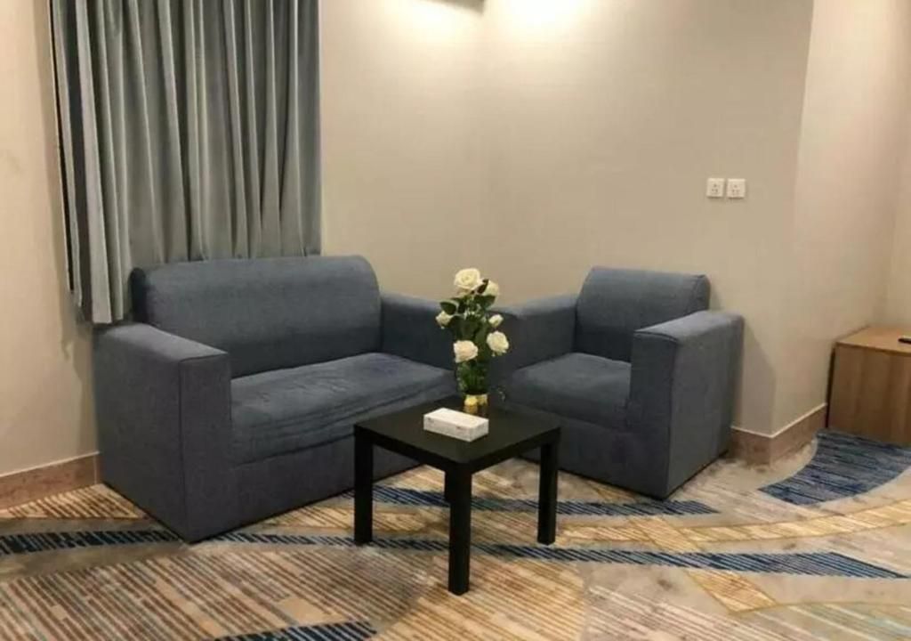 Una habitación con dos sofás, una mesita con un florero y una alfombra estampada.