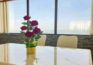 A table with a vase of flowers, a window with a view, and a stone wall. - Elaf Al Sharqyah Al Aziziah Hotel  (Al Khobar)