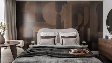 A modern bedroom with a large bed, a bedside table, a small round table, and a dresser.