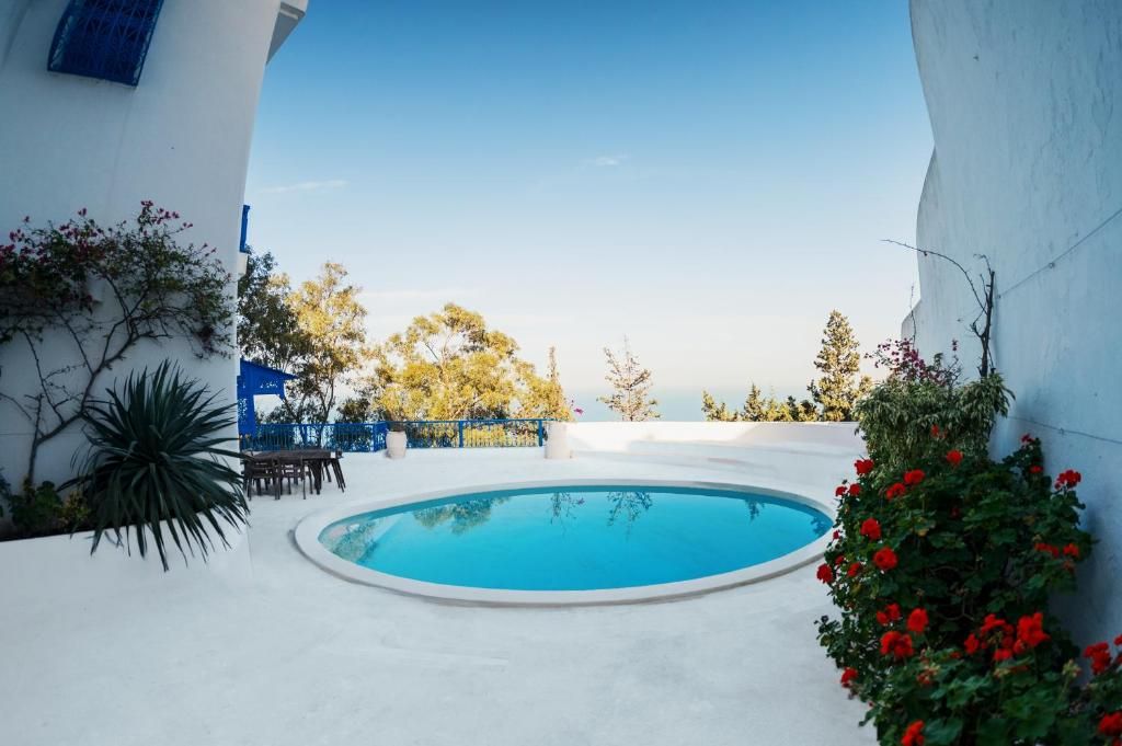 Una piscina con vistas al mar, rodeada de muros blancos y algo de vegetación.