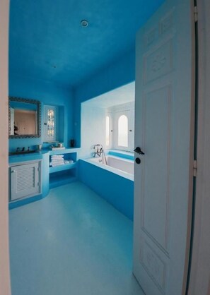 Une salle de bain avec un plafond bleu, une baignoire, un lavabo et une porte.