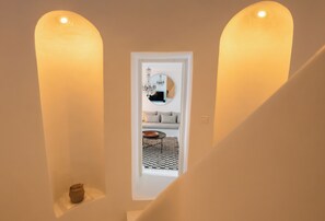 Una escalera con una puerta blanca al final, una mesa pequeña con un cuenco y un jarrón.