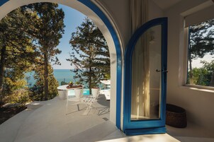 Una habitación con vista al mar, una mesa blanca con sillas y una puerta azul.