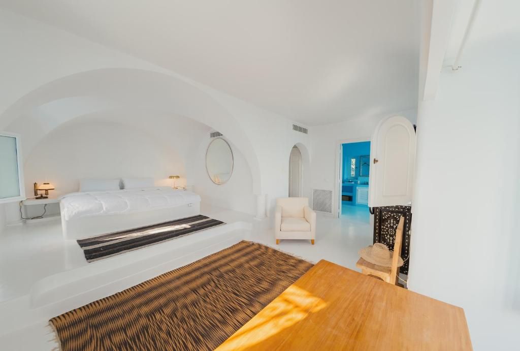 Un dormitorio moderno y minimalista con una cama grande, una mesa de madera y vista al mar.