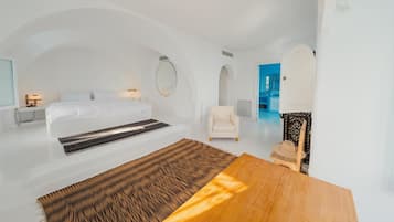 Un dormitorio moderno y minimalista con una cama grande, una mesa de madera y vista al mar.