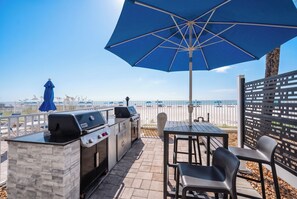 Patio esterno con barbecue, posti a sedere e vista sulla spiaggia.