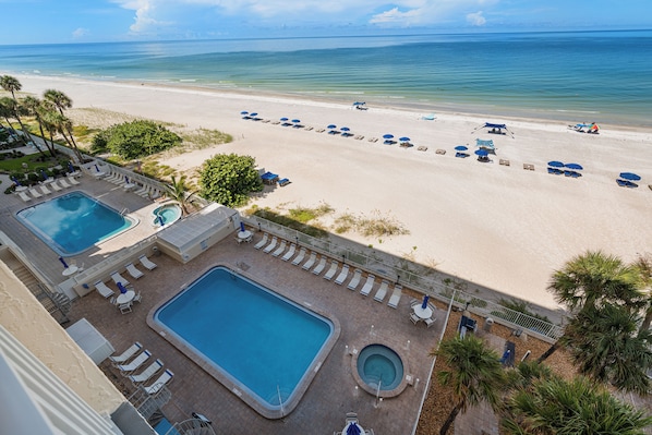 A resort with a swimming pool, a beach area with sun loungers, and a view of the ocean. - New Direct Beachfront 3/2 Upscale, Beachfront Condo, Recliners, Pool, Hot Tub (Indian Rocks Beach)