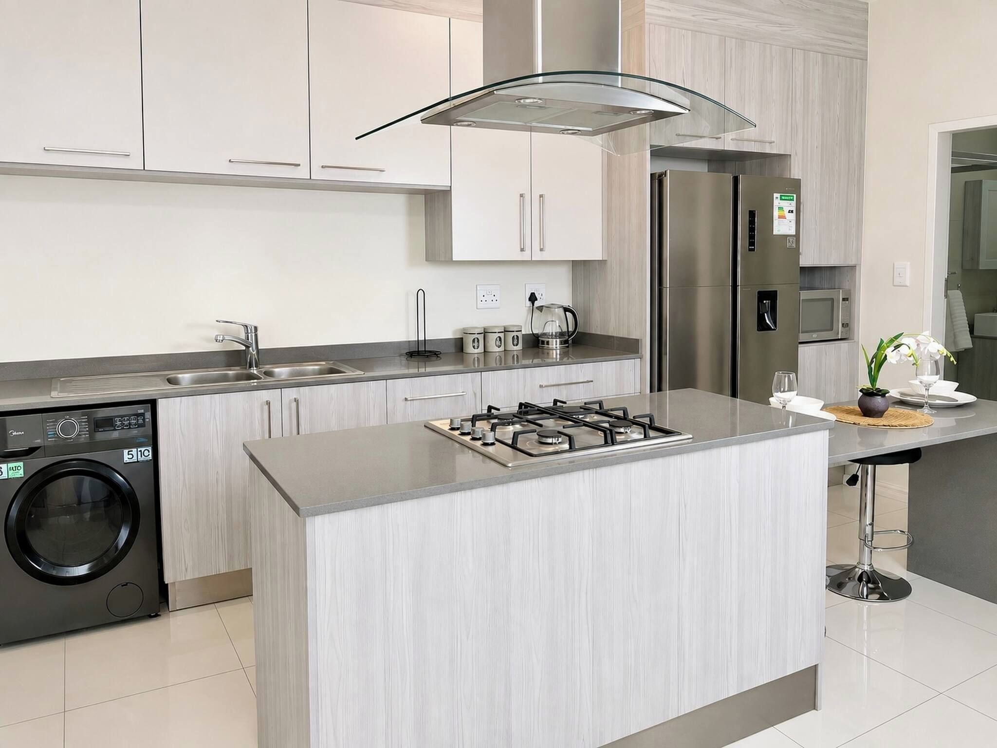 A modern kitchen with a central island, stainless steel appliances, and a built-in washing machine.