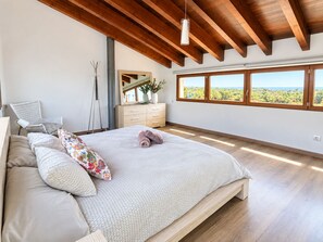 A bedroom with a large bed, a dresser, a chair, and a view of the outdoors through a window. - Can Maimó Estate   (Santanyí)