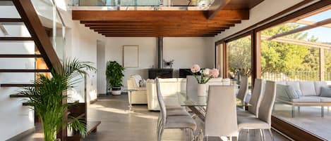 Un interior moderno con una escalera, un comedor y una sala de estar con vistas.