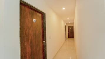 Un pasillo con una puerta de madera marcada con el número 102, que conduce a otra puerta al final.