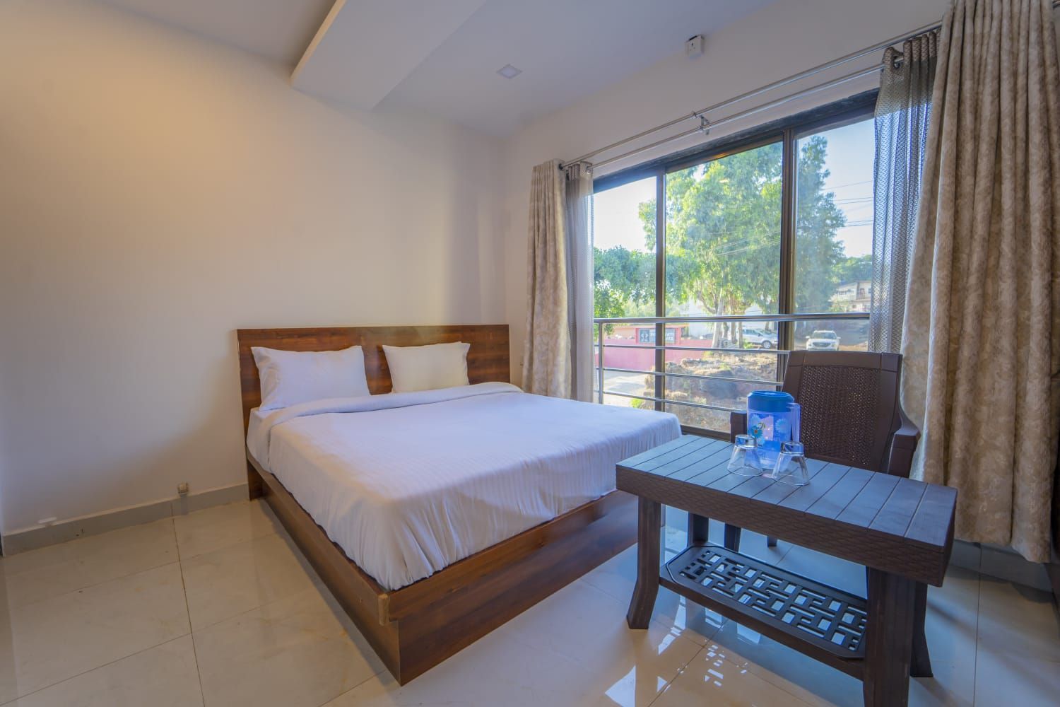 Habitación de hotel con cama, una mesa y vistas al exterior.