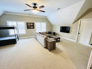 A room with a bunk bed, a sofa, a coffee table, and a TV mounted on the wall. - Private 15-Acre River Estate • Sleeps 14 (New Hill)