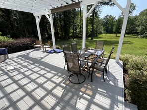 A covered patio with a table and chairs, surrounded by greenery and trees. - Private 15-Acre River Estate • Sleeps 14 (New Hill)