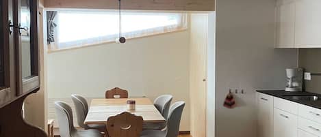 Une cuisine moderne avec un plancher en bois, un coin repas avec une table et des chaises, et un four encastré.