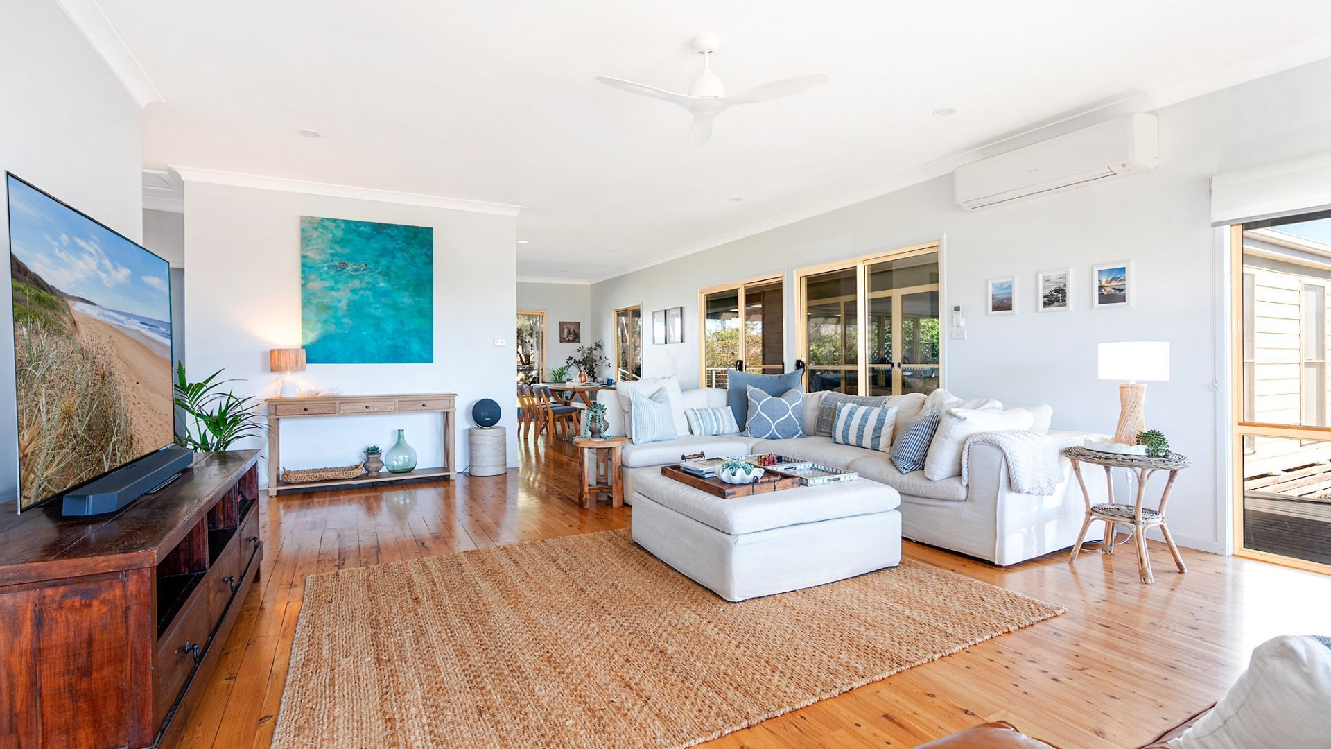A spacious living room with a large sofa, a coffee table, and a television on a wooden stand.