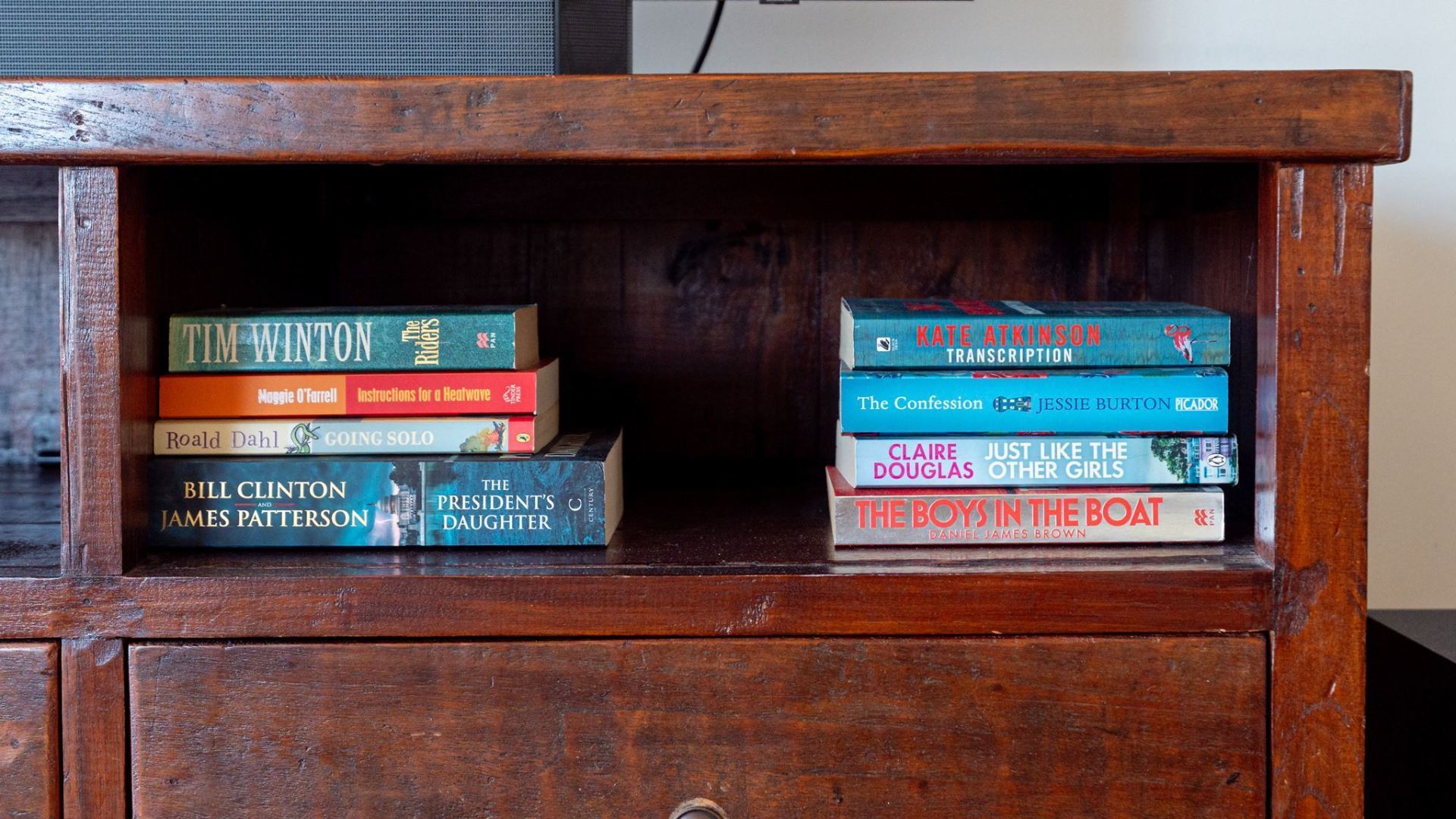 A wooden bookshelf with a variety of books.