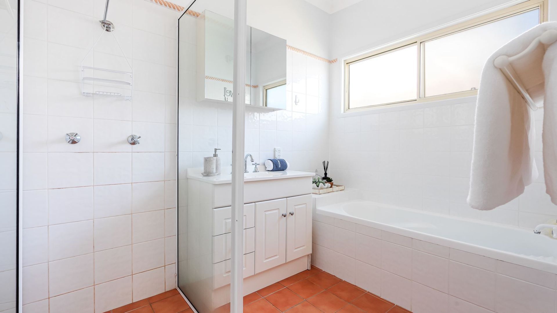 A bathroom with a glass shower enclosure, a white sink, and a bathtub.