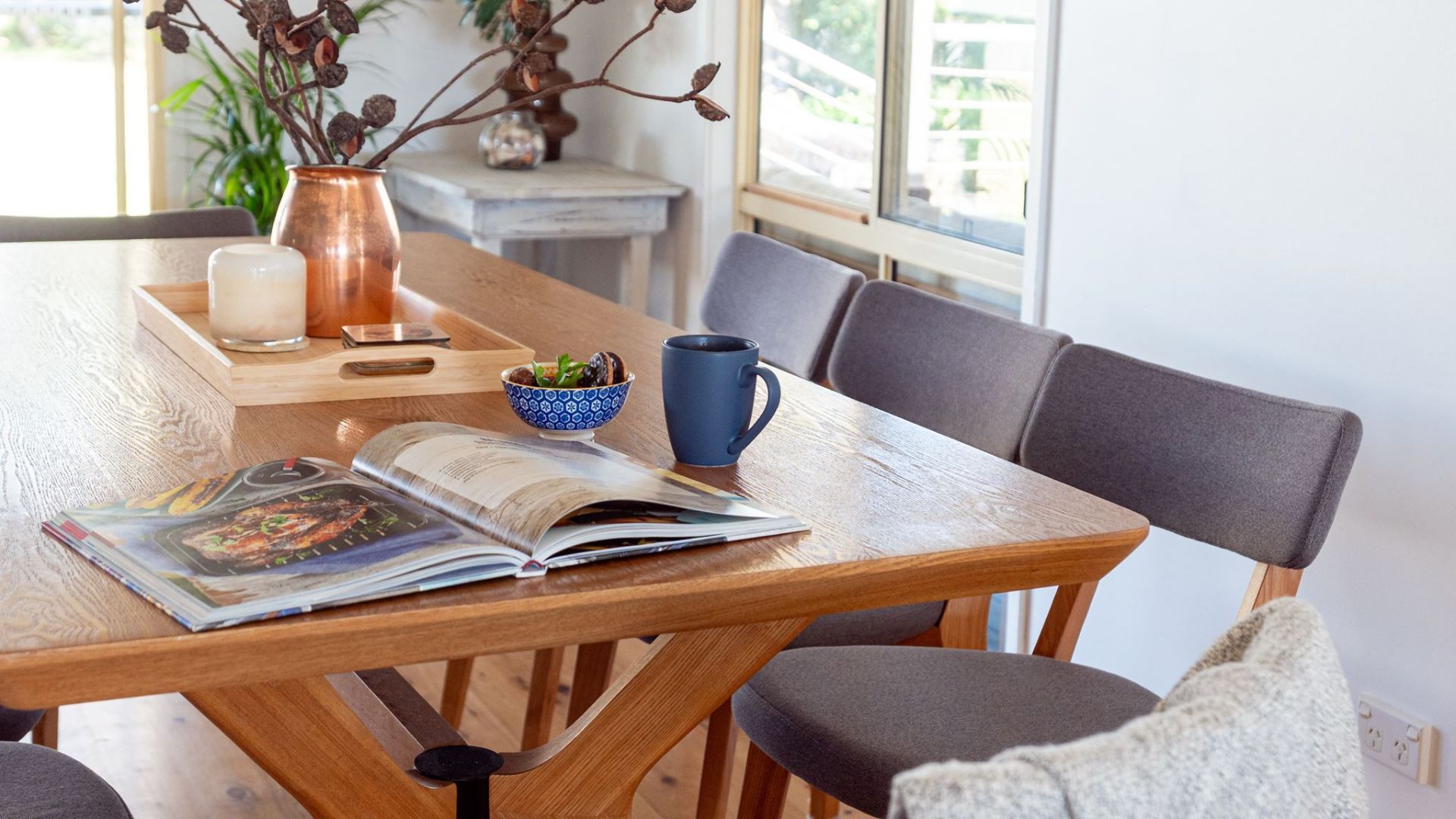 Una mesa de madera para comer con un libro, una taza y un tazón.