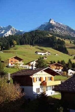 Ein ländliches Dorf mit Häusern und einem Berg im Hintergrund, unter einem klaren Himmel.