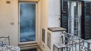 Ein Gebäude mit einem Balkon, einer Tür und einem Tisch mit Stühlen.